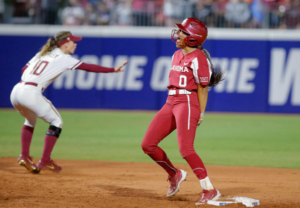 Oklahoma’s Rylie Boone (0) celebrates a double next to Florida State’s Josie Muffley (10) in the third inning during the first game of the Women’s College World Championship Series between the Sooners and Florida State at USA Softball Hall of Fame Stadium in Oklahoma City, June 7, 2023. SARAH PHIPPS / THE OKLAHOMAN