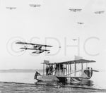 Men stand on a Navy seaplane in San Diego Bay off North Island Naval Air Station with JN-9 airplanes flying above. San Diego’s mild weather made it an ideal test ground for naval aviation, beginning in 1911. San Diego History Center (#6091)