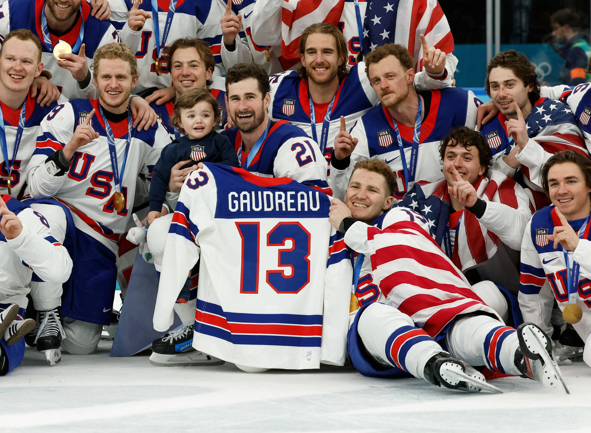 United States players celebrate with a team photo while holding the jersey of Johnny Gaudreau after defeating Canada in the men's ice hockey gold medal game during the Milano Cortina 2026 Olympic Winter Games at Milano Santagiulia Ice Hockey Arena. Geoff Burke / Imagn Images