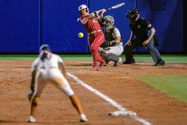 Oklahoma catcher Lynnsie Elam (22) hits a line drive to third during Game 2 of the Women’s College World Series championship series against the Texas Longhorns at USA Softball Hall of Fame Stadium in Oklahoma City on June 8, 2022. NATHAN J. FISH / THE OKLAHOMAN