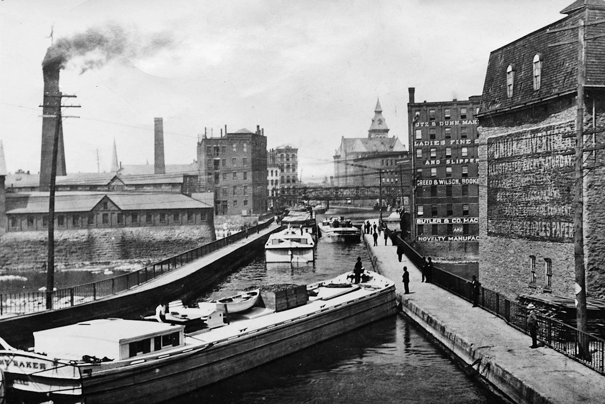 The Erie Canal Aqueduct, looking west, circa 1897 in downtown Rochester. The Aqueduct Building is to the right of the canal in the middle-ground. Rochester Public Library Local History & Genealogy Division