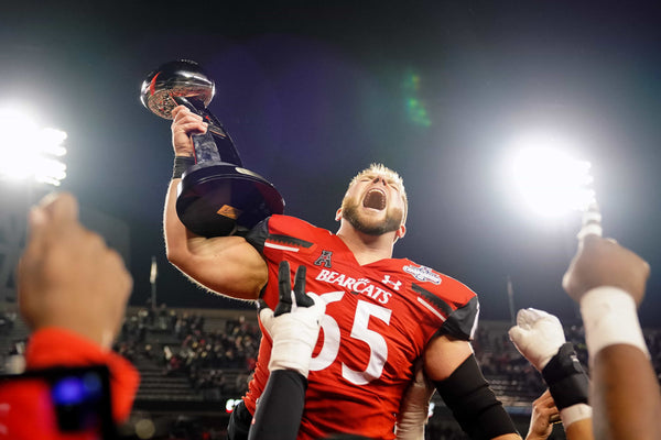 Cincinnati Bearcats offensive lineman Cody Lamb (65) raises the trophy of the American Athletic Conference championship football game, Saturday, Dec. 4, 2021, at Nippert Stadium in Cincinnati. The Cincinnati Bearcats defeated the Houston Cougars, 35-20. The Enquirer