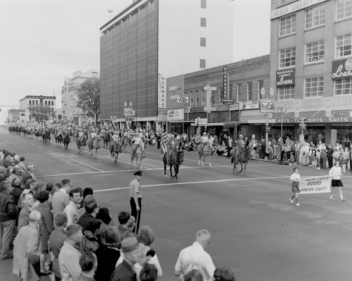 The Dawson County Plum Creek Riders participate in Nebraska’s Centennial Parade on O Street in Lincoln, September 2, 1967. Clark’s Clothes for Men, Household Finance, Anderson Photo Studio, Spoofer Shop, Ten-28 Fabrics, and Norman’s Furniture are all visible. Courtesy Nebraska State Historical Society / #RG0052.PH000003-000020