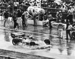 Bobby Unser acknowledges cheers as he splashes through water going into victory lane.  After a sudden downpour at 435-mile mark, Unser was declared the winner. Joe Young/The News