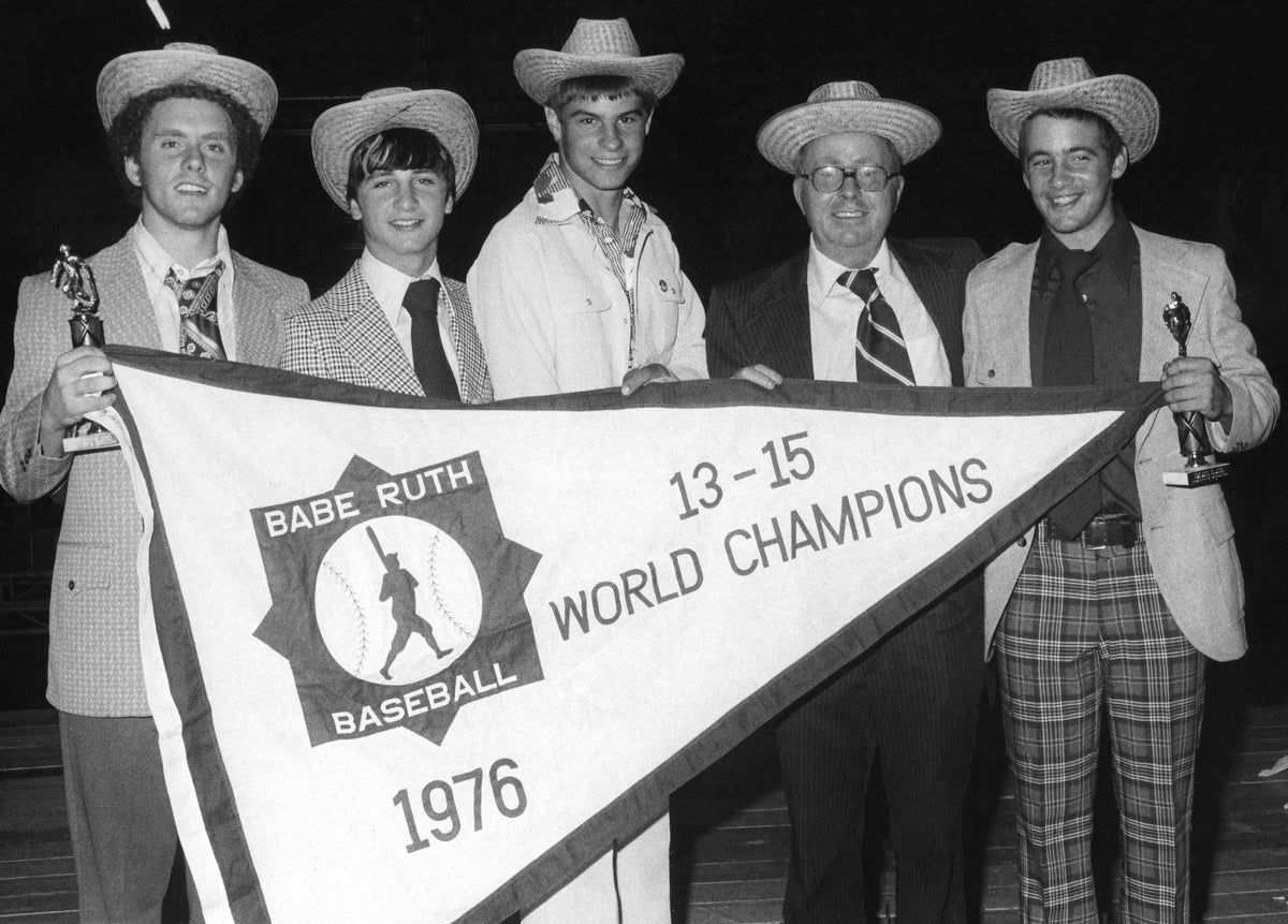 In late August 1976 the Manchester Babe Ruth Tom Woodlock All-Stars won the 13-15 year old Babe Ruth World Series in Pueblo, Colorado against Honolulu, Hawaii. Pictured here at the J.F.K. Coliseum are infielders Phil Spiro, Kevin Emond, Dave Paquette, League Director Peter Poirier, and infielder Bob Beaudet. Photo by Dick Grady. Courtesy Union Leader Archives
