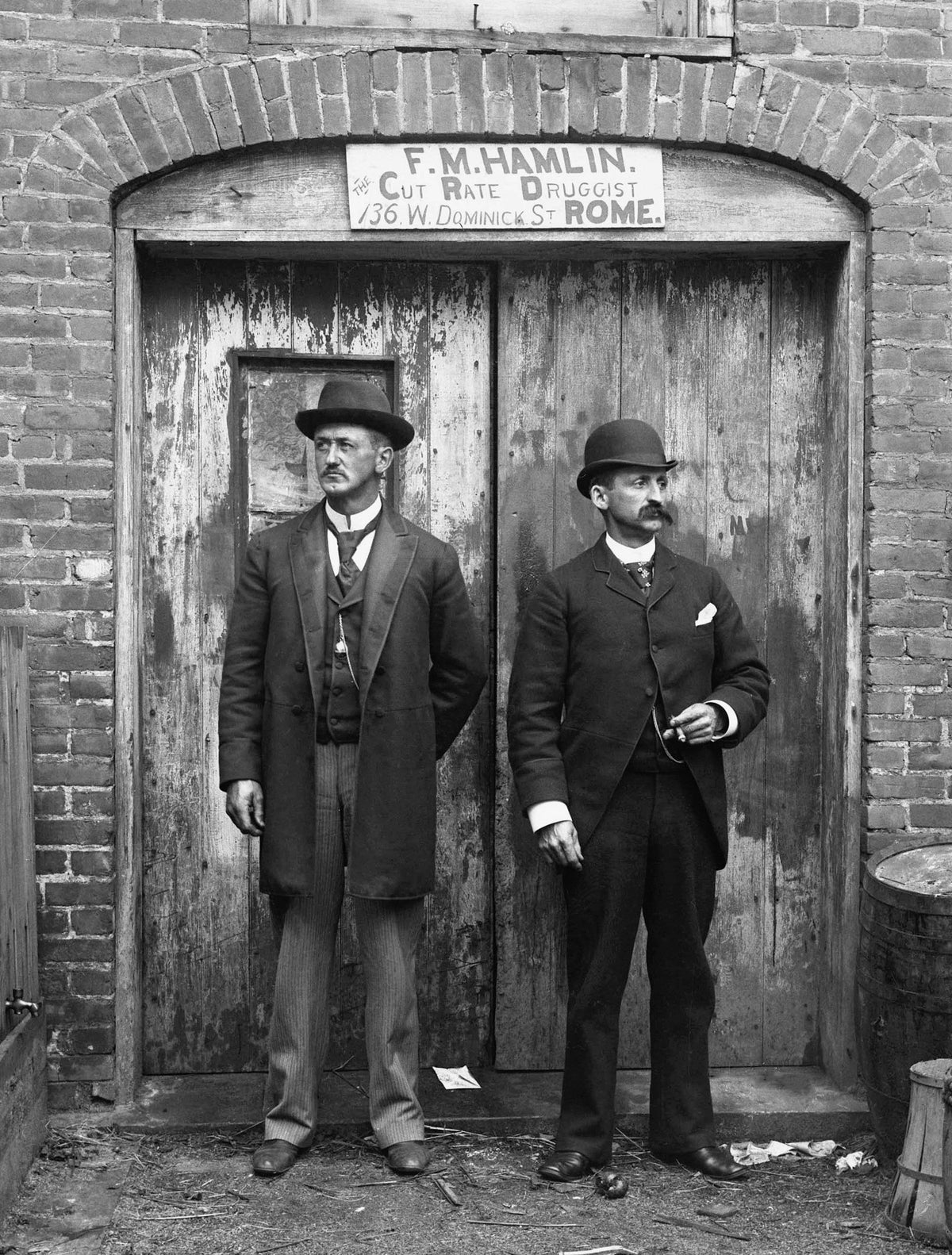 Two men at the front door of F. M. Hamlin, The Cut Rate Druggist, at 136 West Dominick Street, 1900. Courtesy Rome Historical Society / #2018.2.2.147
