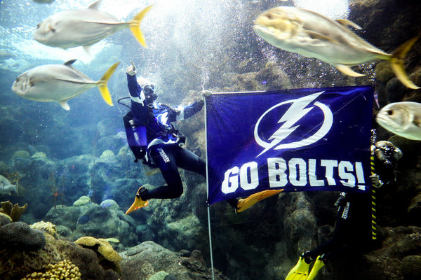Matt Shuttleworth, left, and Elise Herbert, marine operations specialists with The Florida Aquarium, display a Tampa Bay Lightning flag while swimming with the sharks in a show of support for the Tampa Bay Lightning on Sept. 3, 2020, at The Florida Aquarium in Tampa. Tampa Bay Times / Douglas R. Clifford