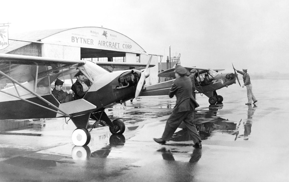 Planes taking off at First Municipal Airport in Albany, October 10, 1954. Inside the plane at left are Cadet Captain M. Friedman and First Lieutenant J. Alvaro, spinning the prop is Major William Brunelle. In the plane at right are Second Lieutenant V. Miller (talking to observer) and Cadet Sergeant G. Turner. Spinning the prop is Warrant Officer A. Murrell. Courtesy Albany Institute of History & Art