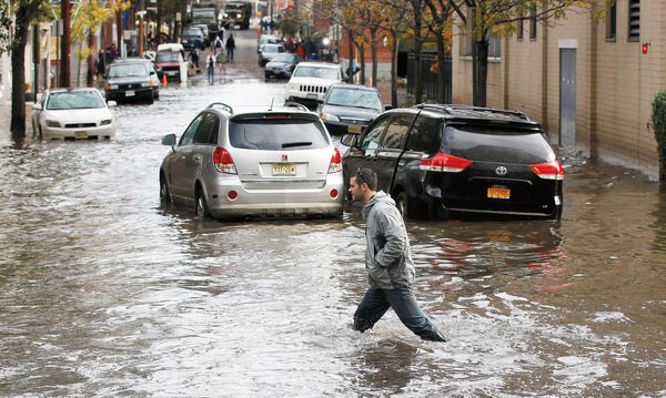 A man walks behind cars swamped by floodwaters on a street in Hoboken. William Perlman / The Star-Ledger