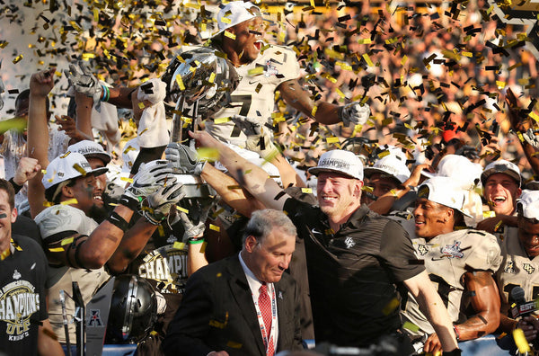 UCF head coach Scott Frost and players celebrate amid falling confetti with the championship trophy after winning the American Athletic Conference Championship Game. Stephen M. Dowell / Orlando Sentinel