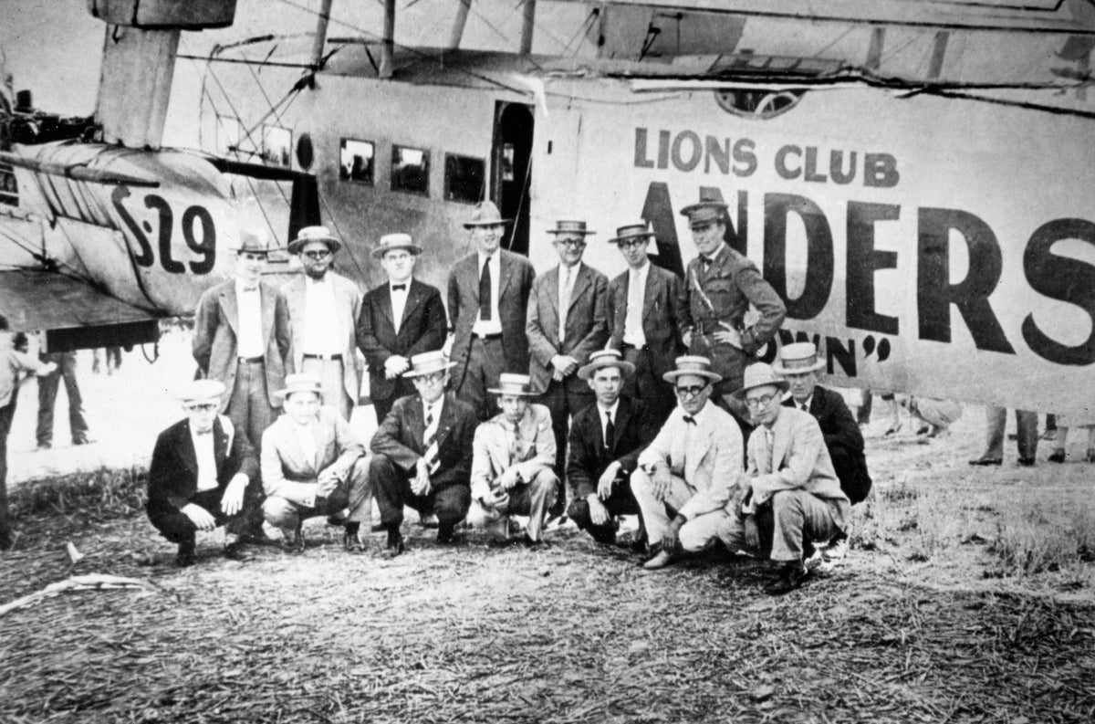 Fourteen members of the Lions Club of Anderson at the old airport in front of an airplane promoting the club, Anderson,1926. The dirt runway airport was located where the Civic Center is currently. Courtesy Anderson County Museum