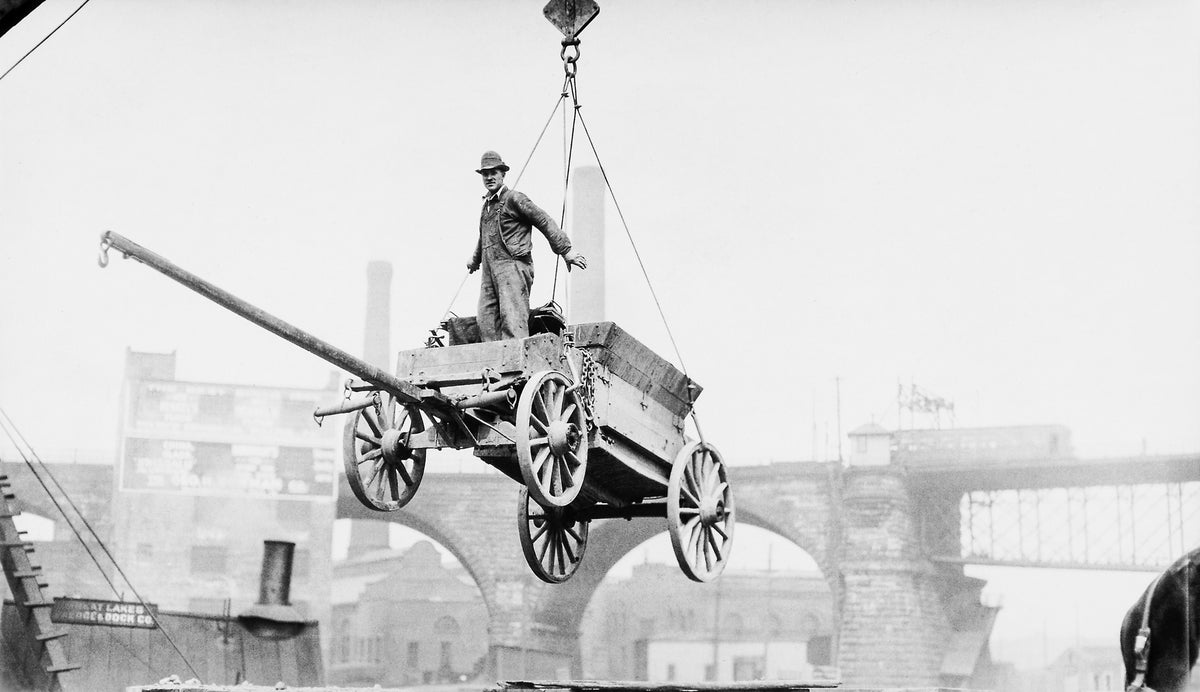 A man and wagon are hoisted into the air from the flats to the bridge deck during construction of the Detroit/Superior bridge, circa 1917. The Superior Viaduct is in the background. Courtesy David M. Thum
