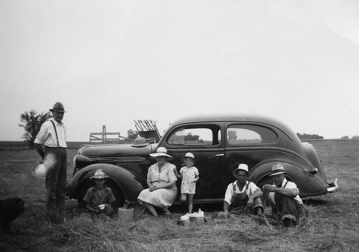 The Johnson family eating lunch in a field in the shade of a 1940s automobile, circa 1940. Courtesy Nicollet County Historical Society