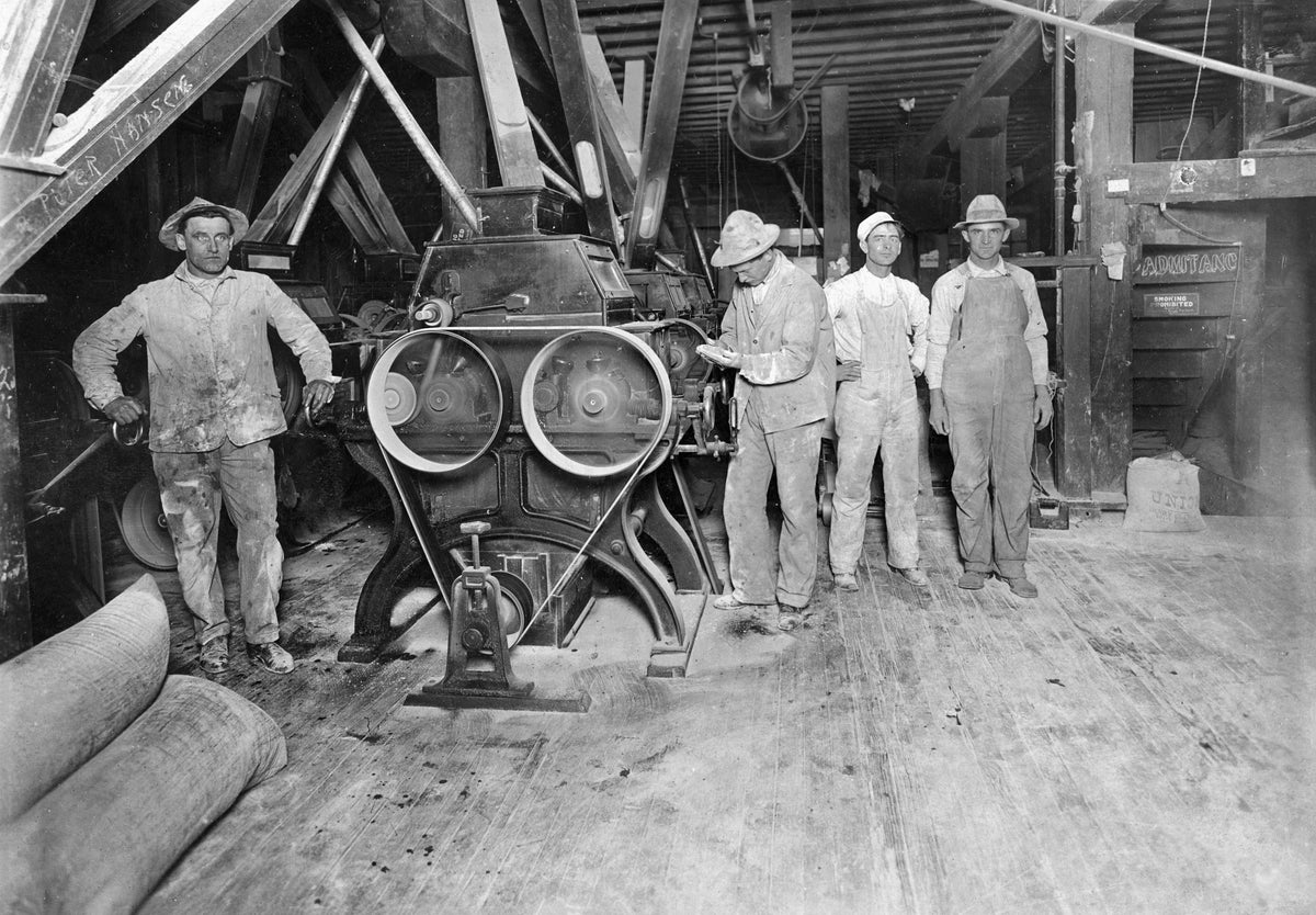 Interior view of the old Glade Milling Company, Grand Island, circa 1913. Fred Glade is pictured at the far left, and the man working at roller stand is Art Glade. Both were sons of Henry Glade, who founded this steam powered flour mill in 1884. The mill was located along West South Front Street between Walnut Street and Wheeler Avenue and faced east toward Wheeler. Courtesy Stuhr Museum of the Prairie Pioneer