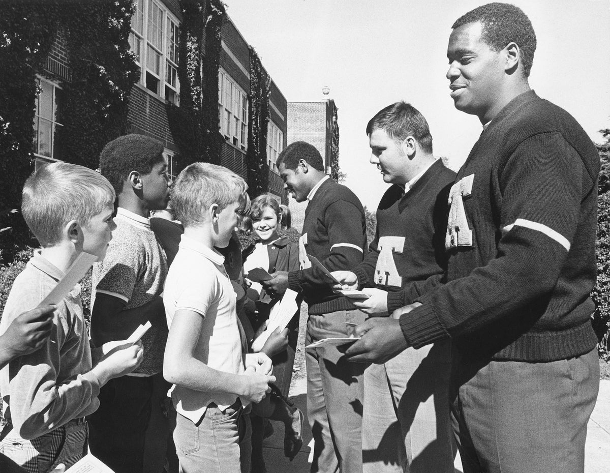 A&T University football players Lorenzo Pearson, John Andrews, and Bill Holmes giving free tickets to students at Aycock School, October 1969. Courtesy The News & Record