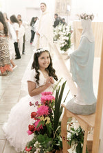 Father Christopher Plant watches in the background as 8 year old Jennifer Berlanga Reyes kneels before the Blessed Mother after her first Holy Communion at Capilla La Divina Providencia in Houston on May 31, 2015. Elizabeth Robertson / Staff Photographer