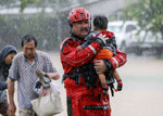 Chad Smith, a Task Force One member from the Dallas Fire Dept., carries Christian Rodriguez, 1, from a rescue boat as people are transferred to a pickup point along Edgebrook Sunday, August 27, 2017. Courtesy Melissa Phillip / Houston Chronicle