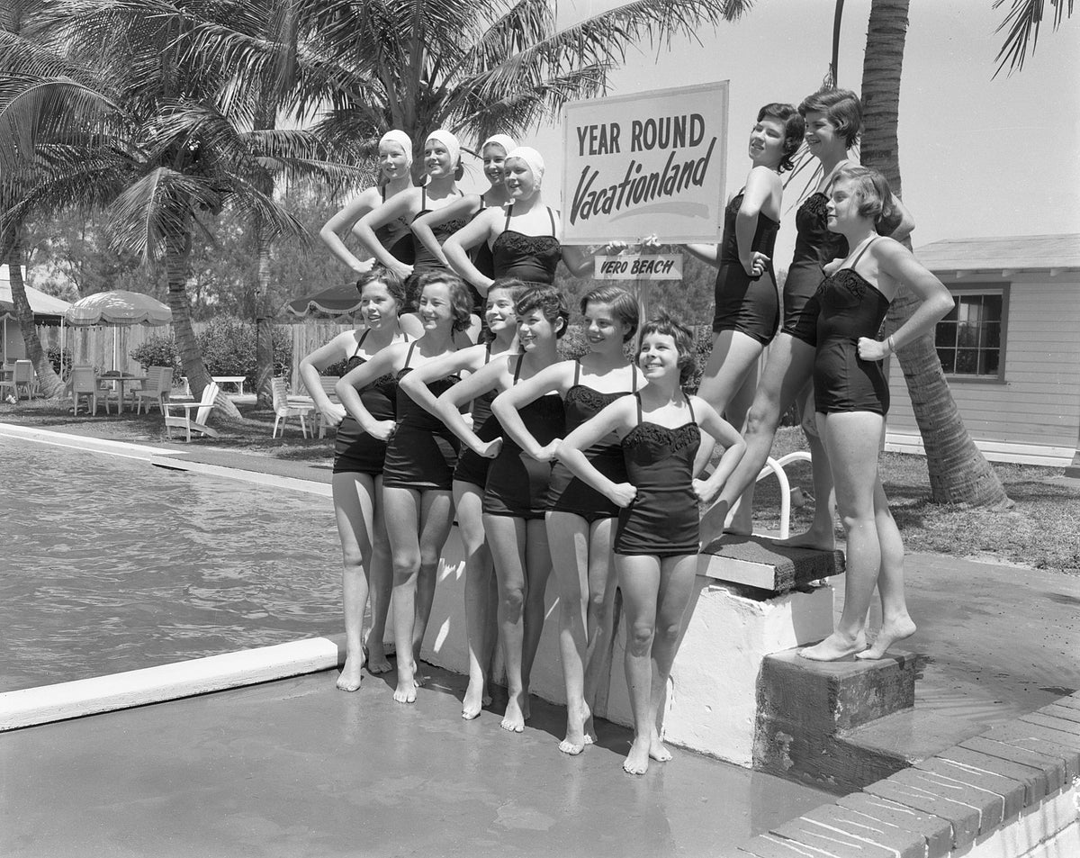Thirteen teenage Dolphinettes in dark swimsuits stand pool side by a diving board and sign reading “Year Round Vacationland: Vero Beach”, circa 1960. Courtesy Indian River County Historical Society Collection, Archive Center, Indian River County Main Library