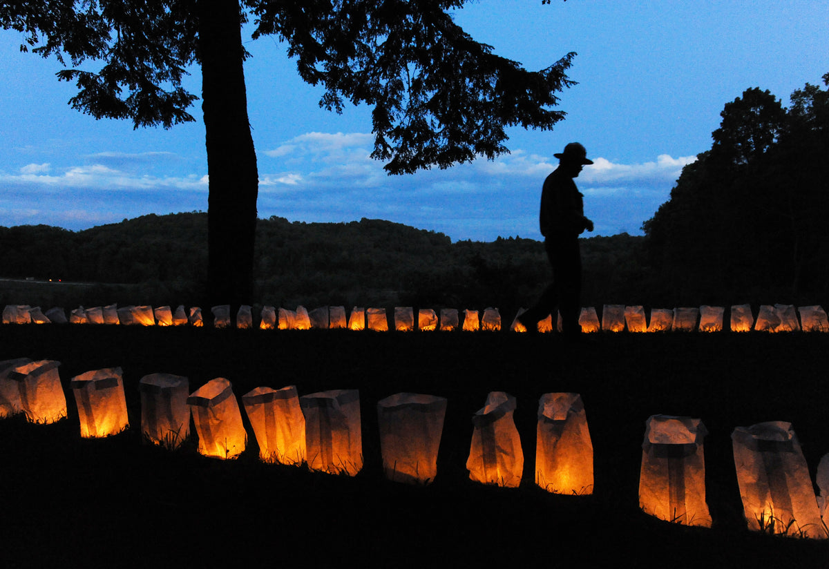 Nathan Koozer, a park ranger at the Johnstown Flood National Memorial in St. Michael, walking among some of the 2,209 luminaries placed on the breast of the former South Fork Dam at the memorial on the 128th anniversary of the disaster, May 31, 2017. Each luminary represented a victim of the disaster which devastated the city of Johnstown 14 miles downstream when the breast of the dam failed to hold back swollen Lake Conemaugh. Courtesy The Tribune-Democrat