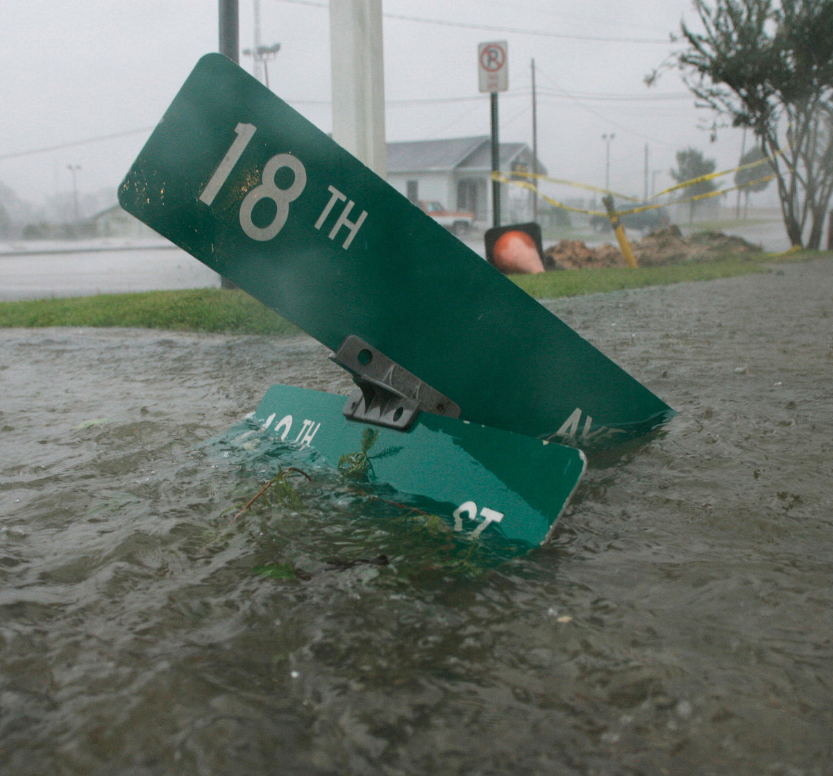 A street sign from the intersection of 18th Avenue and 12th Street lies in flowing water during Hurricane Katrina.