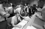 Flight controllers gather around the console of Glenn Lunney (seated left), flight director, in the Mission Control Center at the Manned Spacecraft Center. They study a weather map of the proposed landing site in the Pacific Ocean. Among those looking on is Chris Kraft, deputy director, MSC. The Apollo 13 mission had been canceled, and the problem-plagued Apollo 13 crew members were in trans-Earth trajectory attempting to bring their crippled spacecraft back home. CourtesyNASA