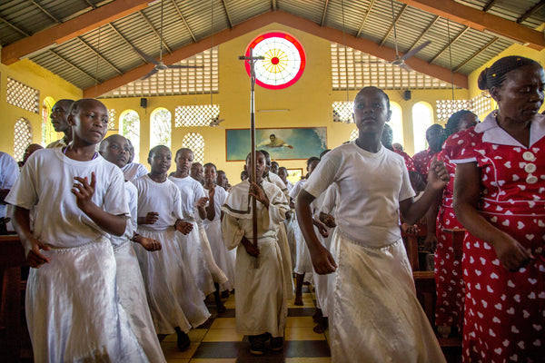 Young female dancers sway in rhythm as altar boys process up the aisle of St. Francis Xavier parish at the start of Sunday Mass. To the right, in red, members of the choir call out "Lord, God," as the congregation replies "Save the children."  For the Philadelphia Inquirer / Georgina Goodwin