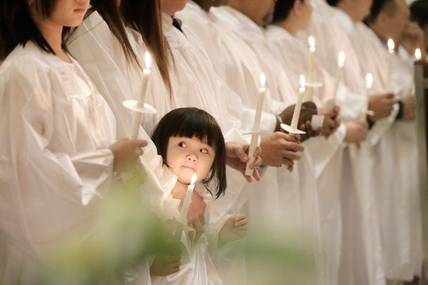 Jillian Nguyen, 3, the daughter of immigrants from Vietnam, peeks around during a baptism ceremony at St. Helena Catholic Church in Philadelphia. Jillian was baptized along with her parents, Stanley Nguyen and Thuong Dinh, and her sister, Lillian, 10. Elizabeth Robertson / Staff Photographer