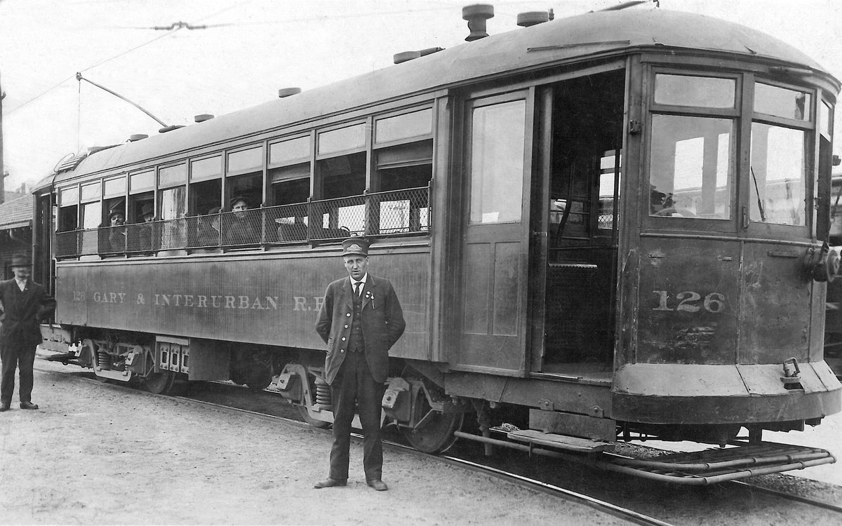 A passenger looks on as conductor George L. Johnson of Gary poses by the streetcar he operated for the Gary & Interurban Railroad. The route included Fourth and Broadway to 45th Avenue and back, then to Valparaiso, returning to Gary via the Flint Lake area. They also serviced the Hammond and East Chicago areas. The streetcar was a vital mode of travel between 1908 and 1947. Courtesy Betty Izynski