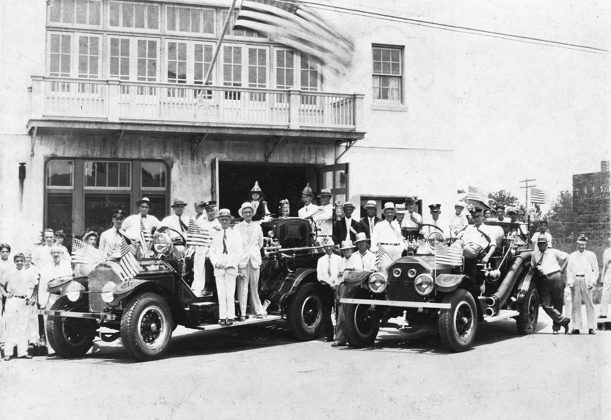 Pascagoula Central firemen, dignitaries and children, circa 1930. Driver in the truck on the left is Mr. Grandlund. Also in the photo are John Watts and Mr. Walter Gulley.