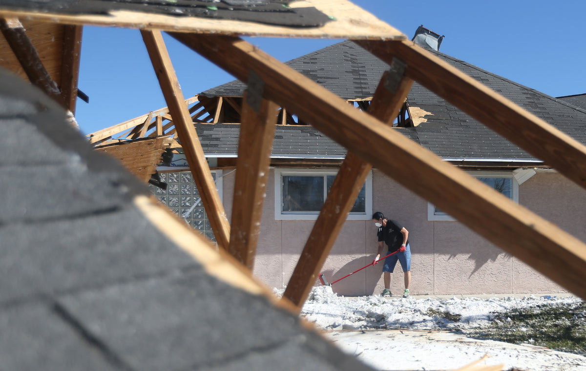 Volunteer Aimee Shcaffer sweeps up debris near a detached roof on October 21 at Operation Spay Bay. Courtesy Patti Blake / The News Herald ^^ center light rgba(40,40,35,0.5)