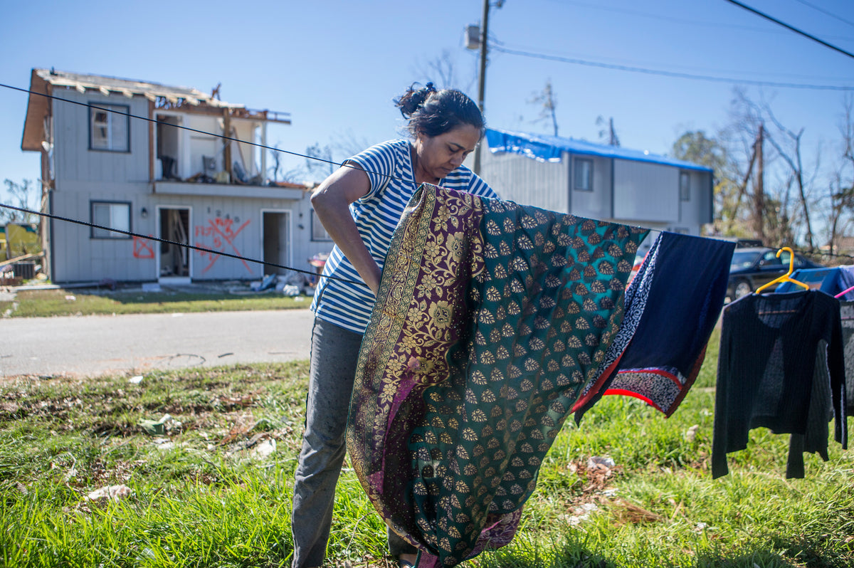 Hamlata Patel uses detached and broken power lines to hang her clothes as her house stands mostly without a roof behind her on October 21 in Panama City. The Patel family returned to Panama City after Hurricane Michael to find their home destroyed and looters stealing family jewelry and other items. Courtesy Patti Blake / The News Herald