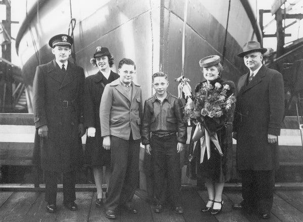 Christening of YOG-64, a U.S. Navy gas tanker, built at Albina Engine & Machine Works shipyard, 1945. Doris Allen Bardy christened the tanker with champagne on January 18, 1945. From left: Man and woman in uniform unidentified, Gordon Allen Bardy, Walter J. Bardy, Jr., Doris Allen Bardy, and Walter Joseph Bardy. This tanker was completed too late to help during World War II, however, provided fuel and support for ships of the Occupation Forces, and transporting troops back home. Courtesy The Oregonian