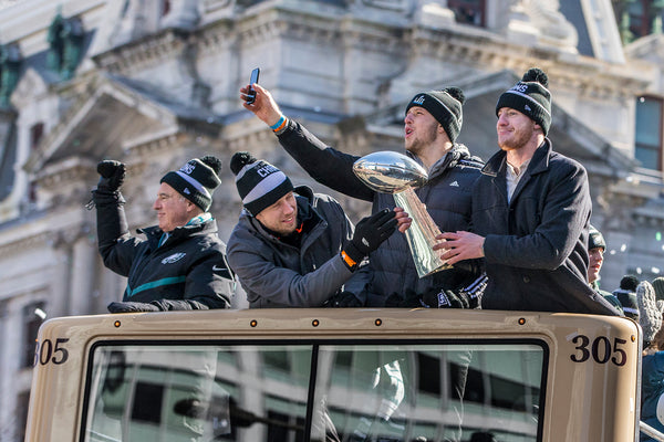 With City Hall in the background, Eagles quarterbacks (from left) Nick Foles, Nate Sudfeld and Carson Wentz show off the Vince Lombardi Trophy aboard their bus. At left is Eagles owner Jeffrey Lurie. Courtesy Michael Bryant / Staff Photographer