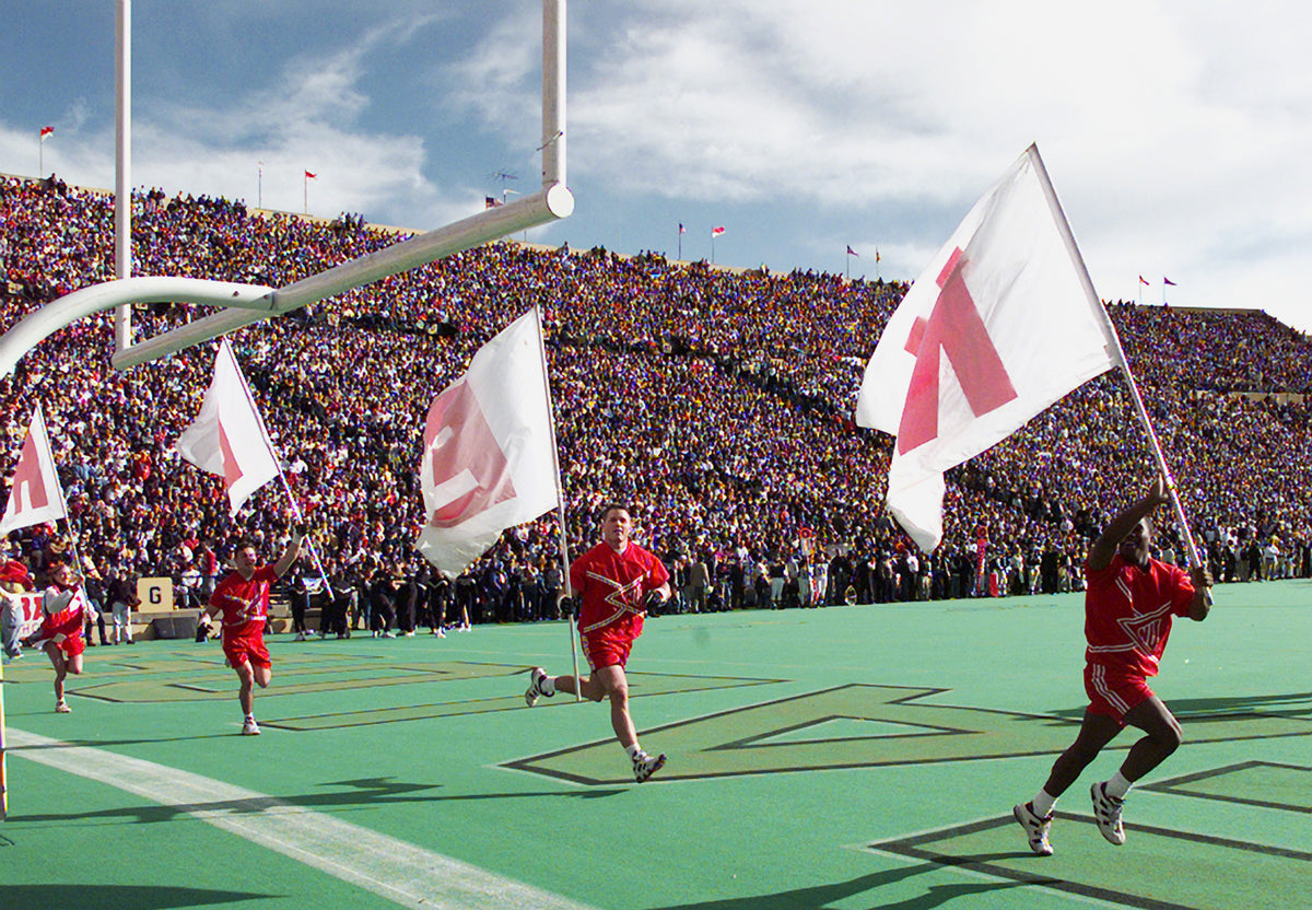 The Nebraska yell squad carries Husker flags onto Folsom Field before the game in Boulder. Courtesy Lincoln Journal Star