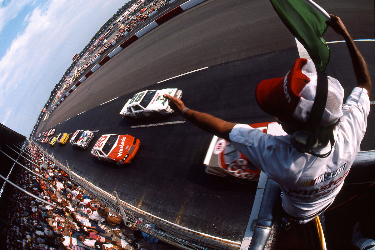 Drivers are given the one-lap-to-go signal from the starter as they prepare to go back to green flag racing following a caution period during the running of the 1985 Southern 500 at Darlington Raceway. Eventual winner Bill Elliott passes under the flag stand, followed by Buddy Baker (No. 88), Cale Yarborough (No. 28) and Ron Bouchard (No. 47). Elliott won the Winston Million bonus. CourtesyISC Images & Archives via Getty Images