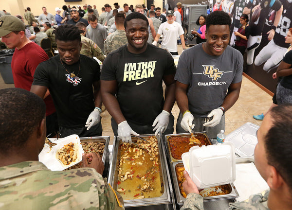 UCF football players, from left, Rod Sylvestre, Jordan Johnson and Anthony Roberson serve a meal to National Guard soldiers at the UCF football facility. Stephen M. Dowell / Orlando Sentinel