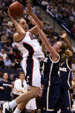 UConn’s Diana Taurasi dishes off in the lane as Notre Dame’s Kelsey Wicks defends during the second half of a 2002 Big East game against Notre Dame at the Hartford Civic Center. Sean D. Elliot / The Day