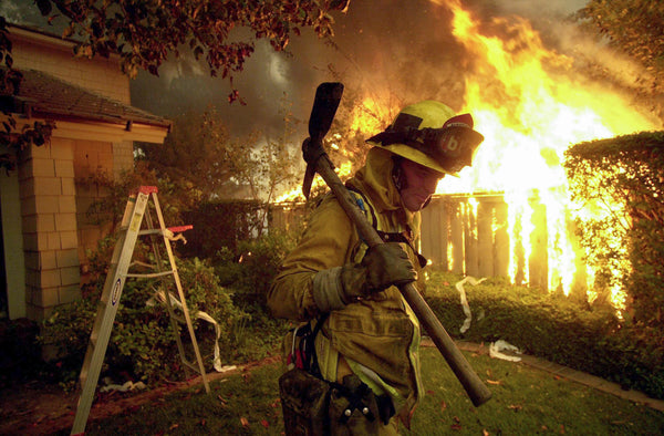 Fireman Eric Brue retreats from a fully engulfed home that he tried to save, but the fire spread to the attic, Oct. 27, 2003. Brue went home to home knocking down fences and other fuel in an effort to keep homes from burning. Sean M. Haffey / The San Diego Union-Tribune