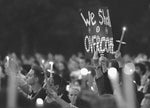 People hold aloft their candles and a sign stating "We Shall Overcome"  during the singing of "God Bless America" during a candlelight Prayer and  Remembrance Service on Old Main lawn on Friday, Sept. 14, 2001. Craig Houtz/Centre Daily Times