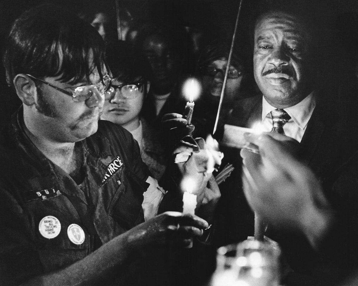 Kent State student Tim Butz, left, and the Reverend Ralph Abernathy, right, hold a candle to what was described as a draft card at the end of a Monday night ceremony in memory of the four students killed May 4, 1970. Abernathy was the president of the Southern Christian Leadership Conference. The ceremony took place Sept. 28, 1970, at the end of the first day of fall classes. Courtesy Akron Beacon Journal