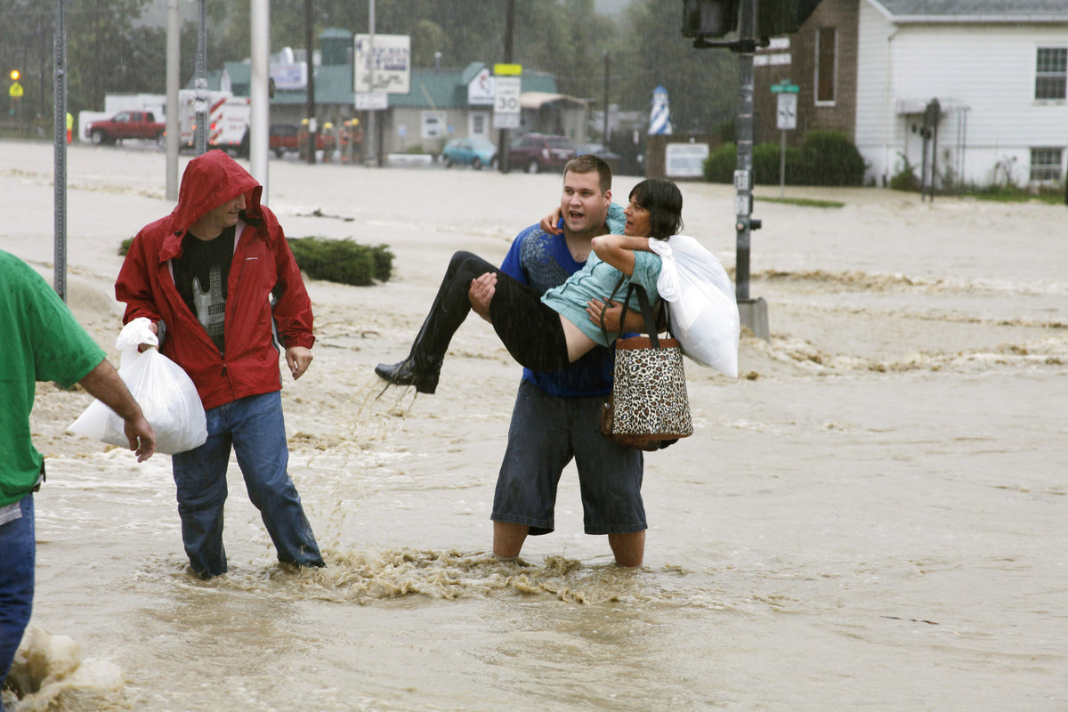 Daniel Witney of Endiott carries Pat Crosby, alongside her husband Chris Crosby, through the flooded intersection of Route 26 and County Road 60 on Wednesday afternoon in West Corners of Endicott. The Crosby’s were evacuating their home behind Hydro Heaven and had no choice but to cross over the surge of knee-high water covering Route 26. Witney who originally entered the area to fill up his gas tank, immediately began helping evacuates cross the road resembling a shallow river. The Crosby’s plan to stay wi
