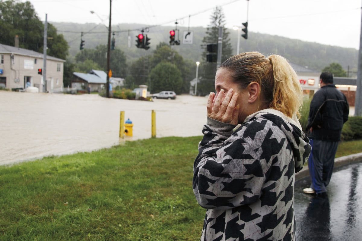 Patty Desmond cries out and covers her face with her hands as she looks on to flooded Route 26 in West Corners of Endicott on Wednesday afternoon. Desmond cannot locate her children and her dogs that have yet to be rescued by emergency personnel. CASEY STAFF/ Staff Photo