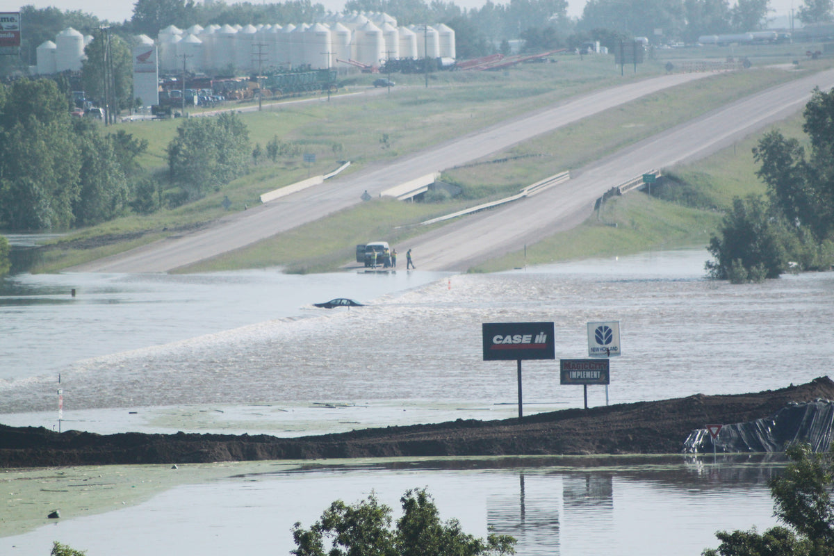 Officials work to determine how to remove a car overcome by water rushing across the highway on the east side of Minot.