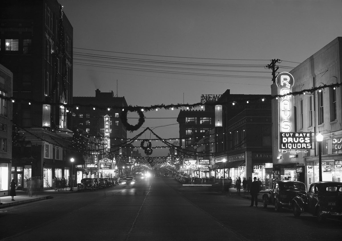 Joplin’s downtown commercial district was aglow with Christmas spirit in 1941. An assortment of colored lights and traditional evergreens were strung across Main Street, inviting visitors and Joplin citizens to begin their Christmas shopping. The photo was taken at 5th and Main looking south.