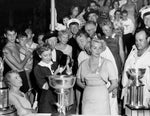 Presentation of the Silver Cup at Detroit, 1954. Included in the picture in the front row, from left: Mrs. Anna Thompson Dodge, mother of Horace; Suzy Mulford, daughter of John Mulford (pouring champagne into the Silver Cup Trophy); Horace Dodge, peeking around his wife; Gregg Dodge; Jack Bartlow in his racing gear, driver of the winning boat. Courtesy Detroit Historical Society / #2014.039.010