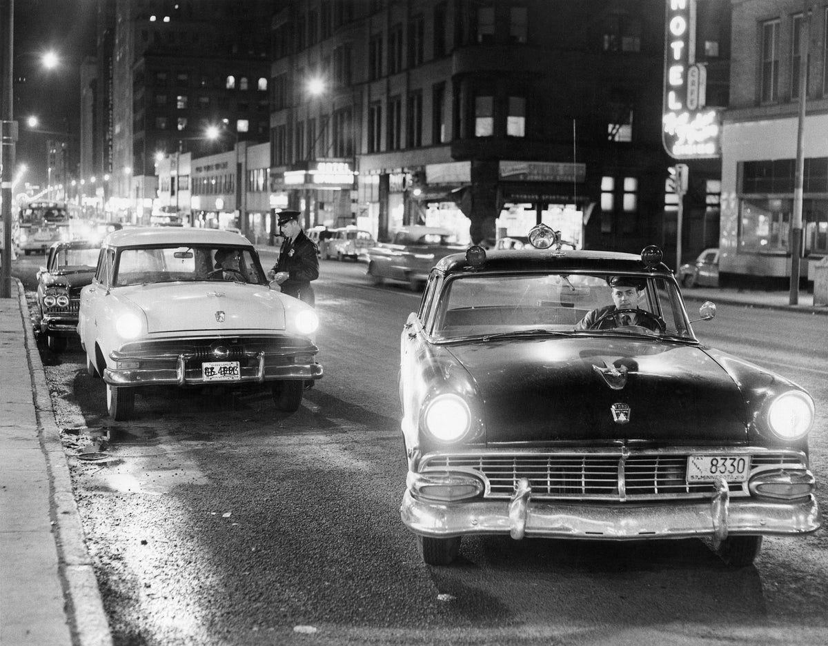 Patrolman Donald Rockwell (left) checking a driver’s license as patrolman Edward McLean parks the squad car at Fifth Avenue West and  Superior Street, Duluth, 1958.  Courtesy Duluth News Tribune