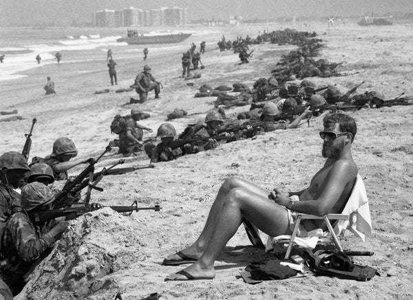 Navy SEAL Bob Meddo acts as a lifeguard during Marine exercises in Coronado while reservists land on the beach in June 1978. Rick McCarthy won honors in the 1979 World Press photo contest. Union-Tribune, photo by Rick McCarthy
