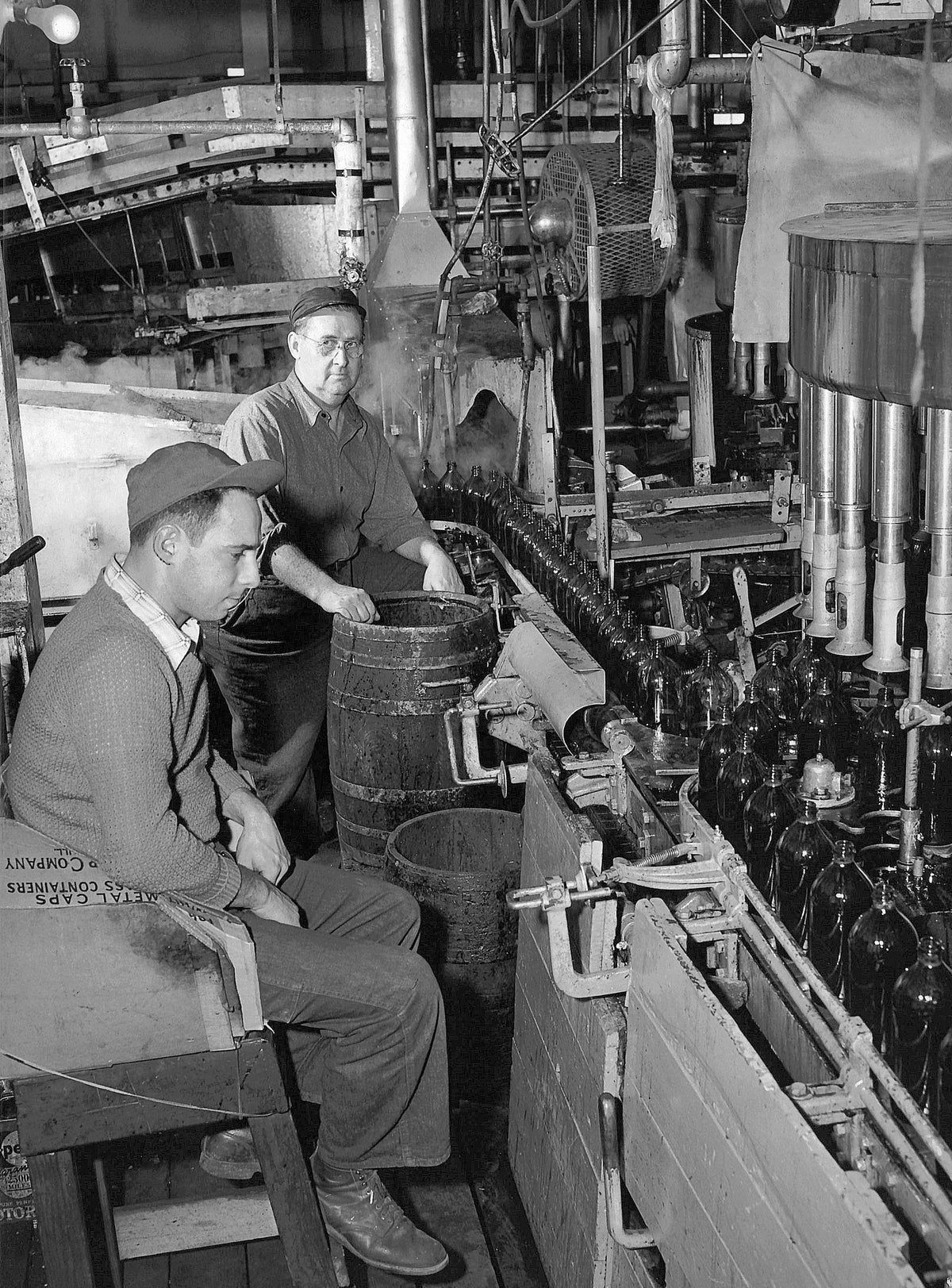 Employees Philip Georgia and Rocco Fallone at the bottle capping station at a cider mill owned by Duffy Mott Company, Voorheesville, 1950. Courtesy Times Union Historic Images