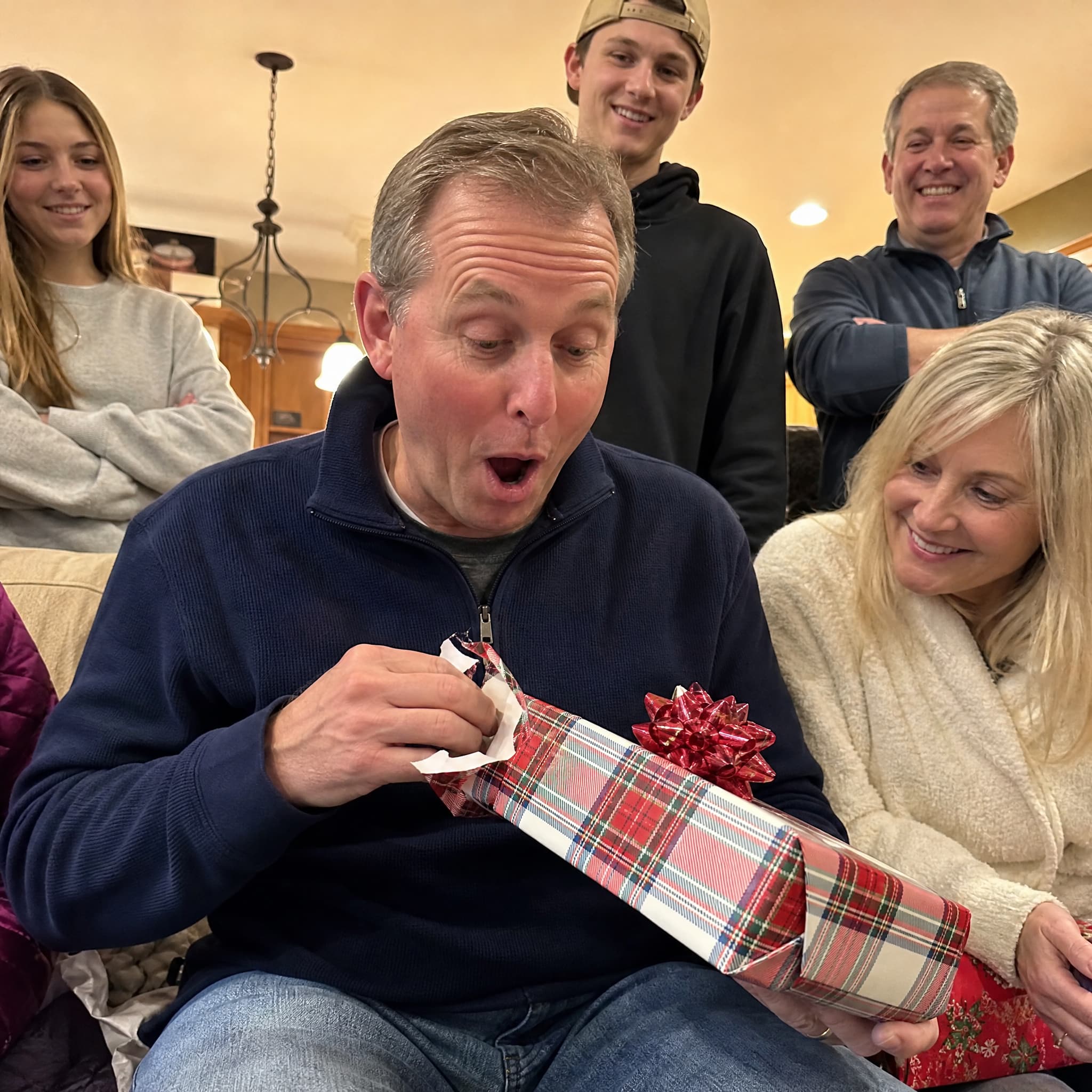 A family gathered close as one of them opens a wrapped Pediment hardcover — the kind of book kept for years.